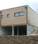 Vue extérieure de la maison écologique en bois réalisée avec un mur pré-usiné (menuiseries intégrées)