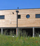 Vue extérieure de la construction d'une maison écologique en bois réalisée avec un mur pré-fabriqué (menuiseries intégrées)