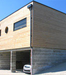 Vue extérieure de la construction d'une maison en bois avec ossature et bardage réalisée avec un mur pré-fabriqué (menuiseries intégrées)