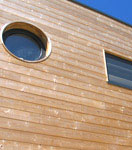 Vue extérieure de la construction d'une aison bois avec ossature et bardage réalisée avec un mur pré-fabriqué (menuiseries intégrées)